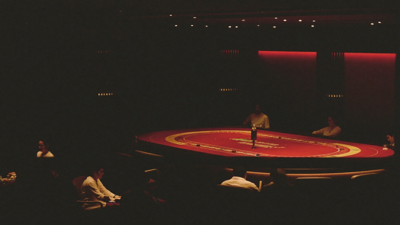 A host pulling a gold door open onto a bright casino floor as a couple step through