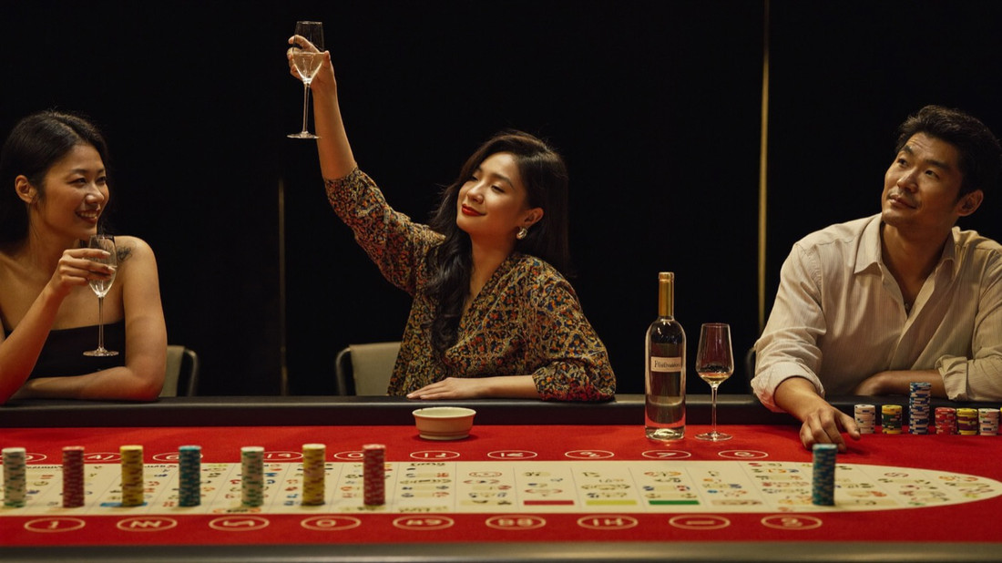 A cashier sliding a doubled stack of gold chips under the counter glass to a smiling couple